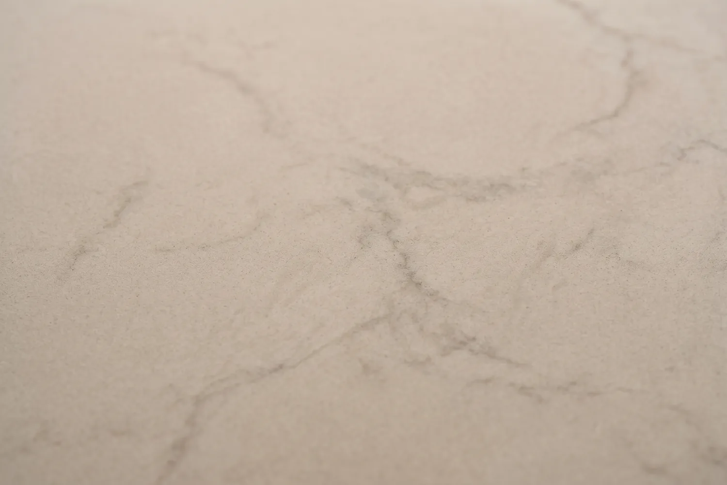 Close-up of a honed quartzite countertop surface showing a smooth matte satin finish with no glossy reflections and gentle muted veining