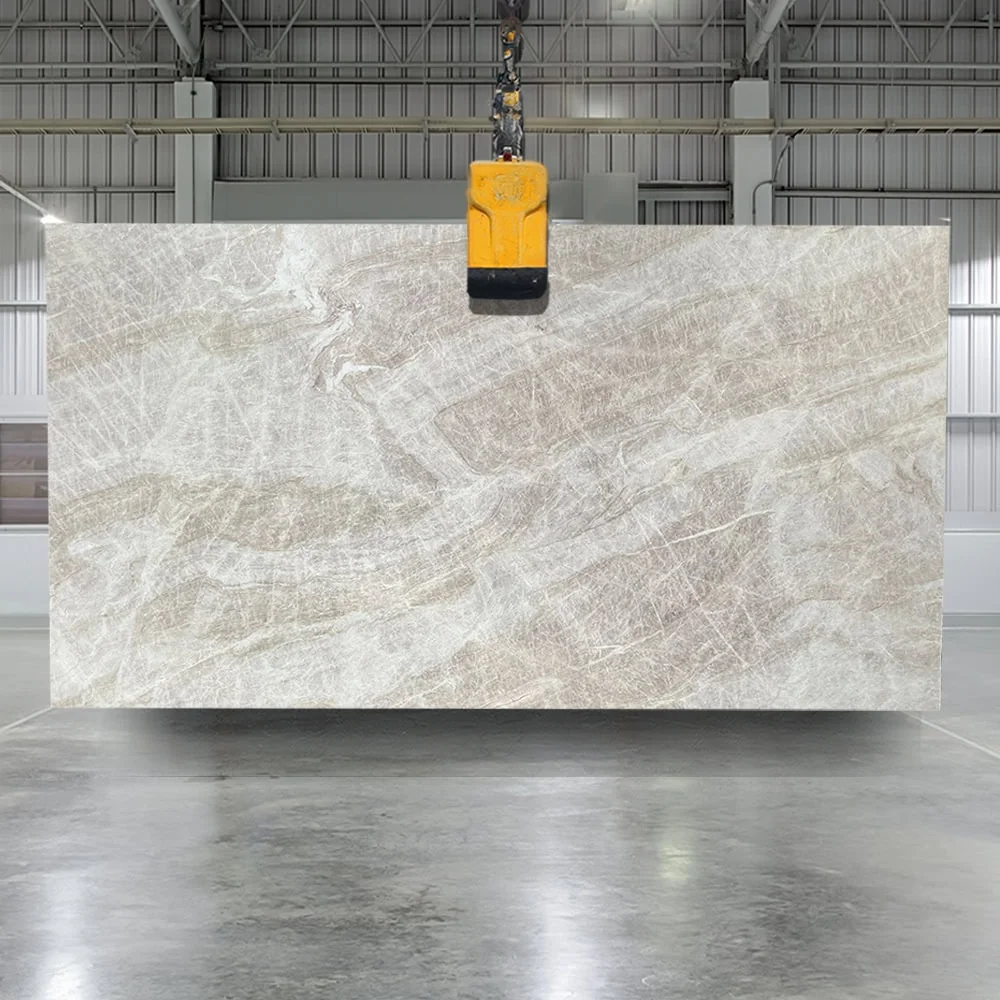 Full leathered Taj Mahal quartzite slab, 3cm thickness, suspended on a lifting clamp in a stone yard showing the softer matte finish and warm beige-and-tan organic patterning characteristic of leathered quartzite